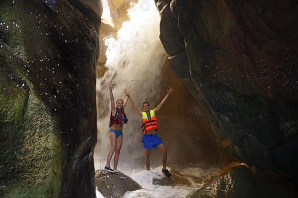 Young couple under waterfall at the canyon of Wadi Mujib