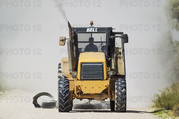 A tractor pulling tyres for grading the parks gravel roads