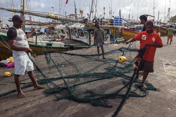 Local men untangling fishing nets in harbour