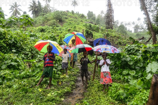 Native women with children with colourful umbrellas in the rain in the village of Rangsuksuk