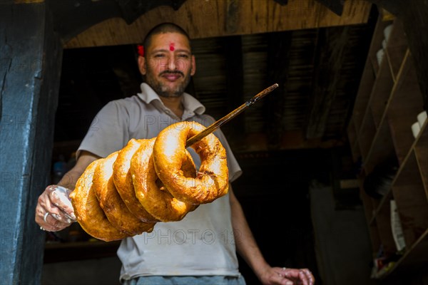 Salesman is displaying some fresh doughnuts on a wooden stick