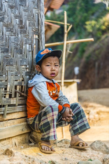 Little boy sitting in front of log cabin