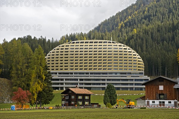 Old Swiss farmhouse in front of modern InterContinental Davos Hotel