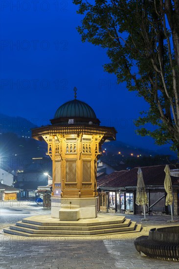 Illuminated Sebilj ottoman-style wooden fountain at sunrise