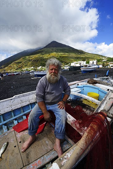Fisherman in his boat in front of volcano on Scari beach