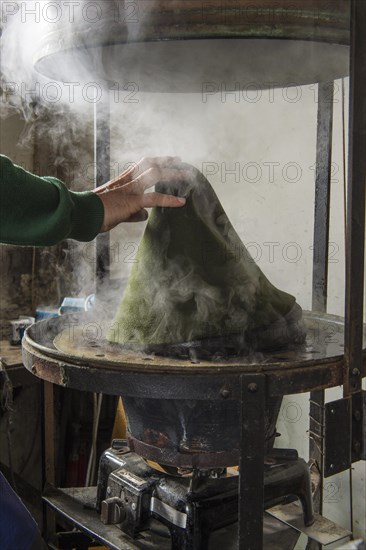 Hand taking hat bodies out of steam boiler