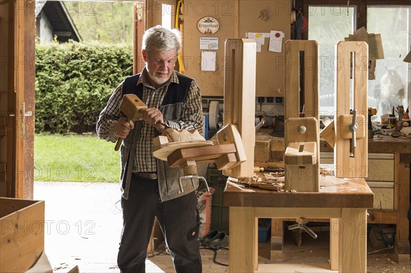 Wooden mask carver using wood carving tools at workbench in workshop