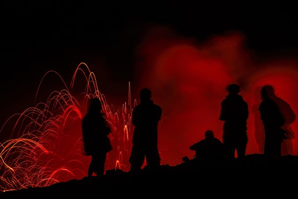 Tourists observe the eruption