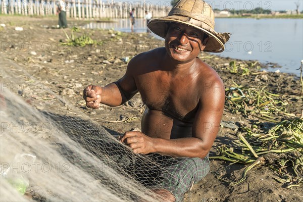 Fisherman mending his net Taungthaman Lake