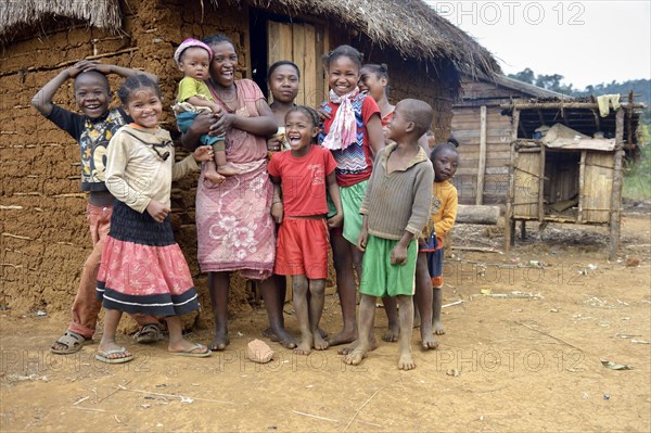 Laughing women and children in front of hut