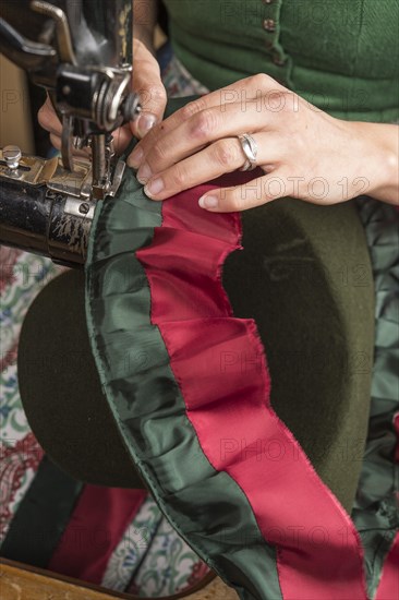 Hands sewing inner lining on a wool felt hat