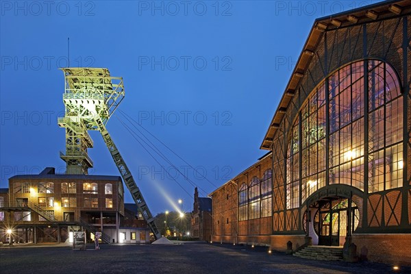 Illuminated machine hall with headframe at dusk