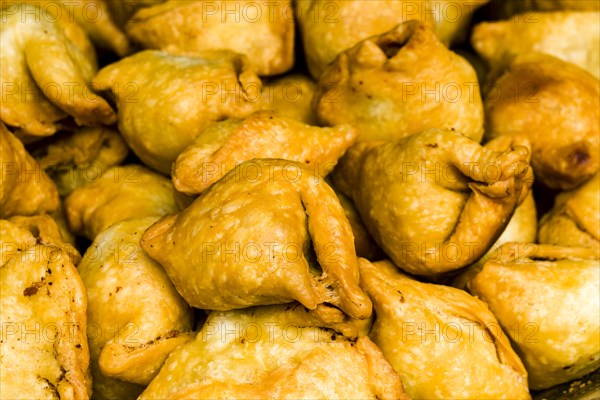 Many fresh samosas are piled up for sale