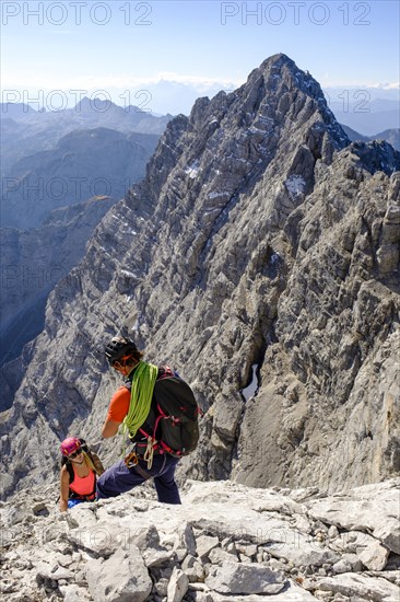 Mountain guide guiding a young woman on a short rope through a rock face