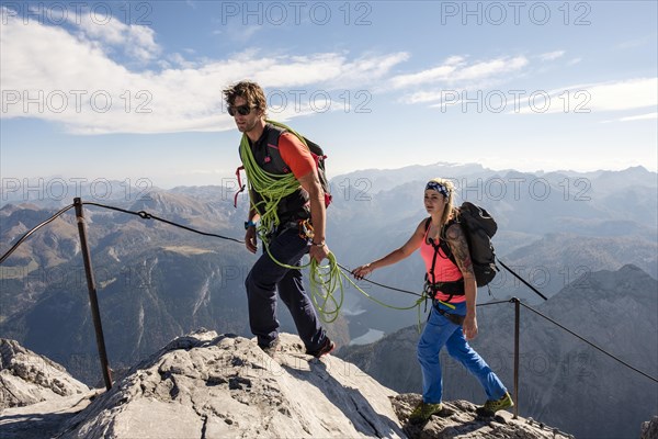 Mountain guide guiding a young woman on a short rope through a via ferrata