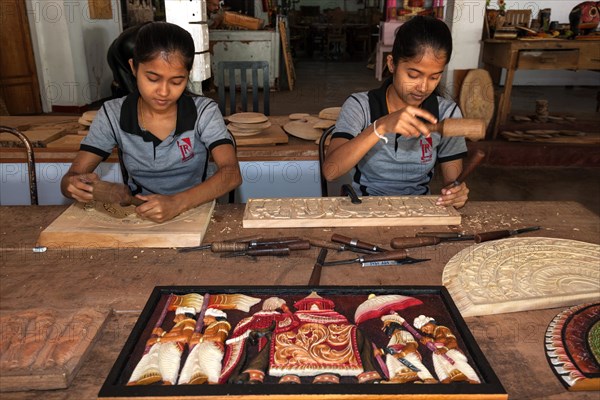 Native Sinhalese girls carving traditional wooden pictures