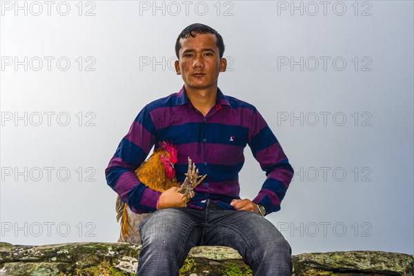 Local man sitting with a rooster