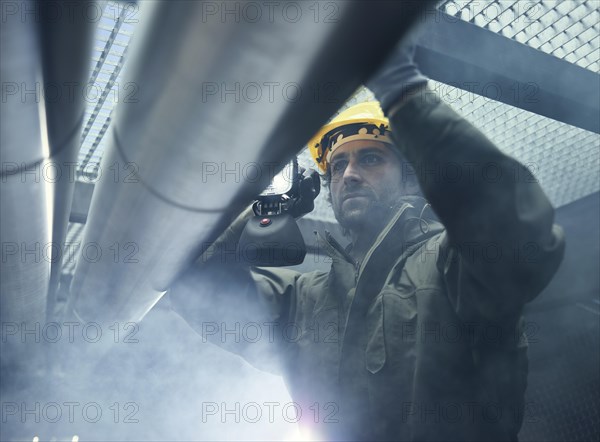 Mechanic with flashlight checking a pipeline