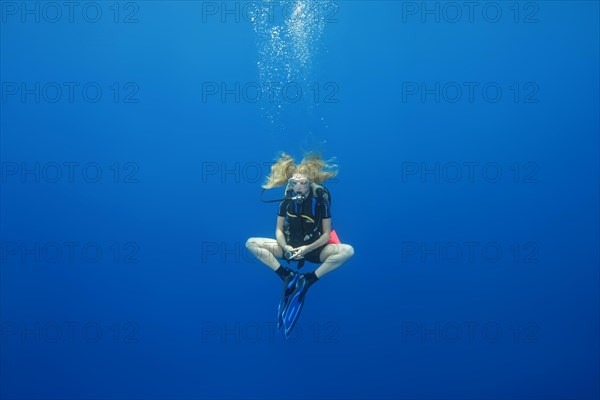 Female scuba diver hung in a lotus pose for a safety stop