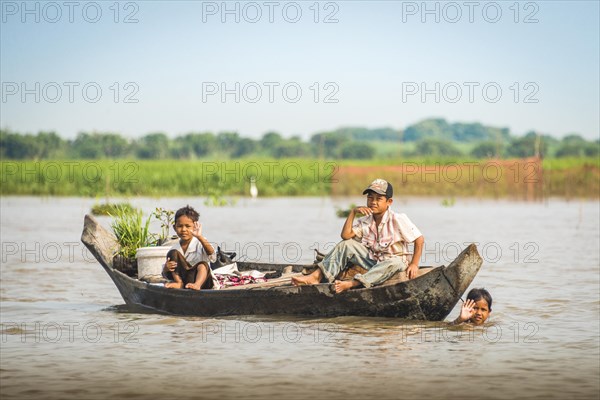 Native children wave on wooden boat