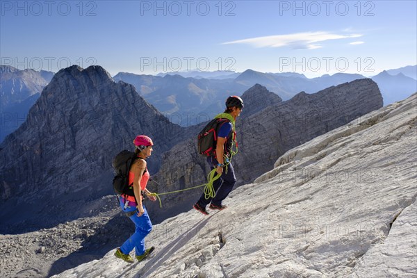 Mountain guide guiding a young woman on a short rope through a rock face