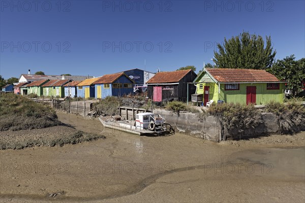 Colorful huts of oyster farmers on a channel at low tide