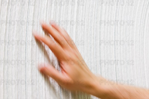 Hand brushes over the side of a wound paper roll in papermaking