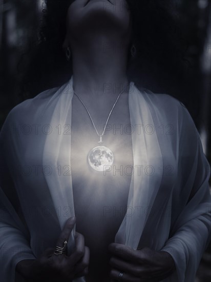 Young woman wearing a magical full moon pendant glowing on her bare chest