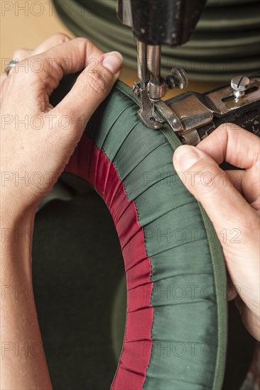 Hands sewing silk ribbon and inner lining on hat edge