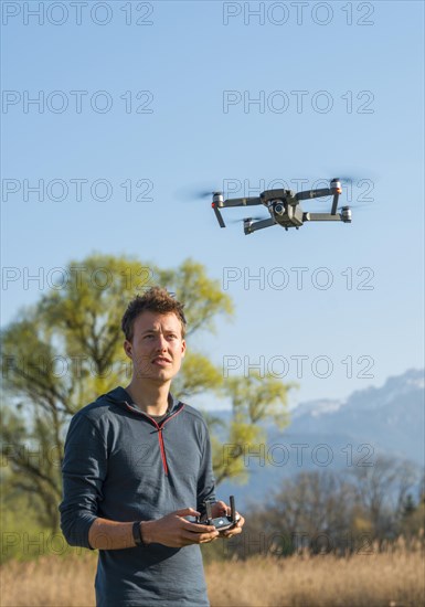 Young man controlling flying quadrocopter