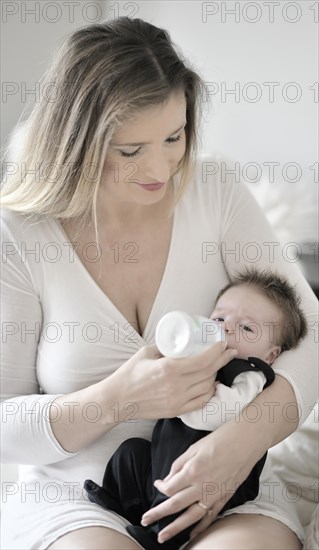 Mother feeds baby with baby bottle