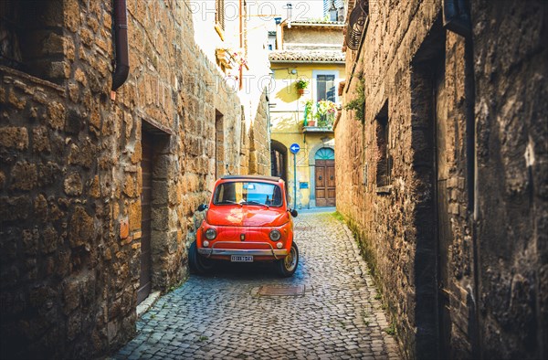 Old red Fiat 500 parked in a narrow alley