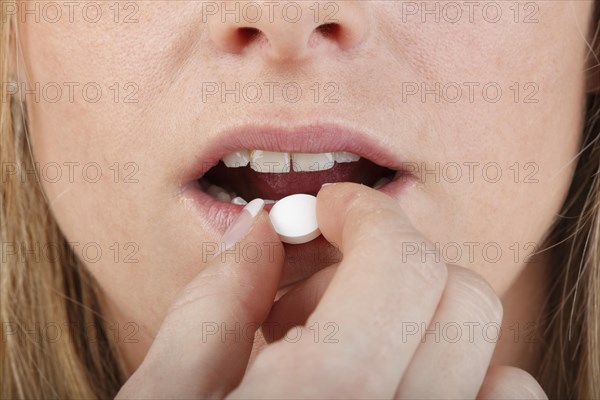 Close-up of young woman taking a pill