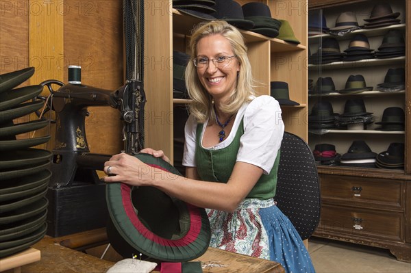 Woman sewing silk ribbon and inner lining on hat edge