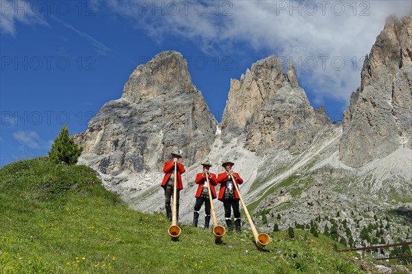 Alphorn players in front of mountains Langkofel and Plattkofel