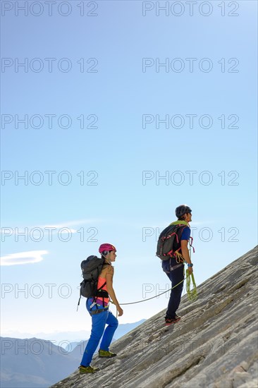 Mountain guide guiding a young woman on a short rope through a rock face