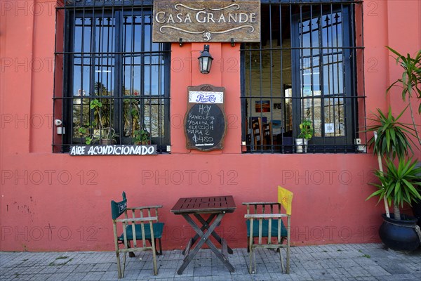 Table with chairs in front of a restaurant with red facade