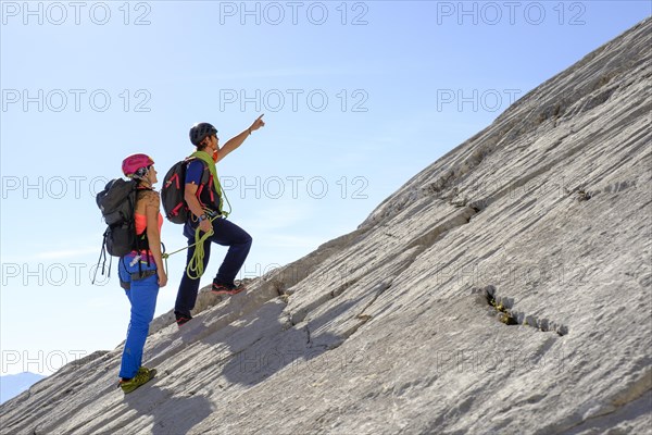 Mountain guide guiding a young woman on a short rope through a rock face