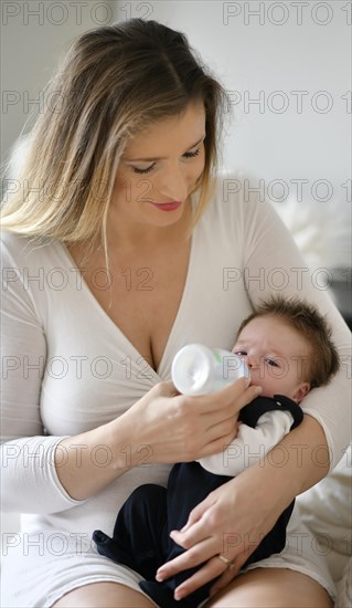 Mother feeds baby with baby bottle