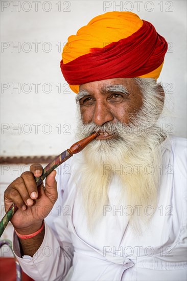 Elderly Indian man with turban smoke hookah