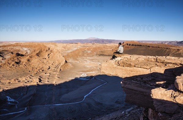 Tourist sits on rock at a viewpoint and looks into the distance