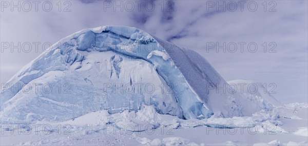 Iceberg seen from frozen fjord