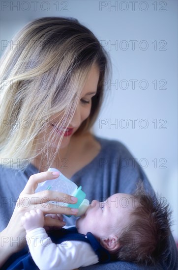 Mother feeds baby with baby bottle