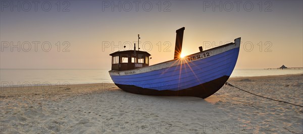 Fishing boat on beach at sunrise