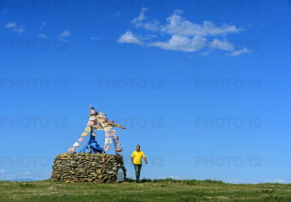 Mongolian man performing prayer ritual beside ovoo