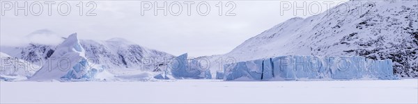 Panoramic view of snow-covered mountains seen from a frozen fjord