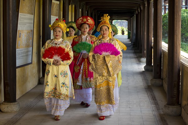 Vietnamese extras in traditional robes walking through imperial palace Hoang Thanh