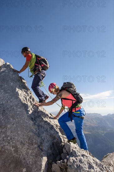 Mountain guide guiding a young woman on a short rope through a rock face