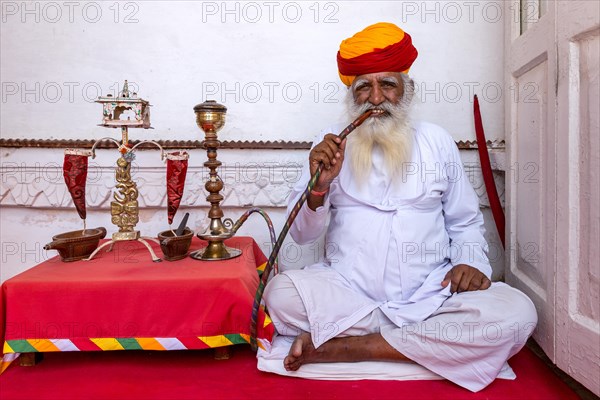 Elderly Indian man with turban smoke hookah