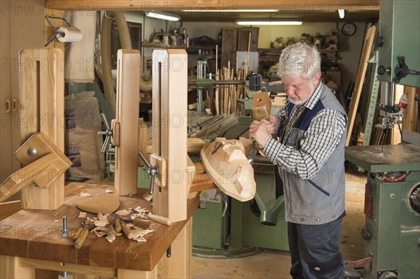 Wooden mask carver using wood carving tools on a wooden block